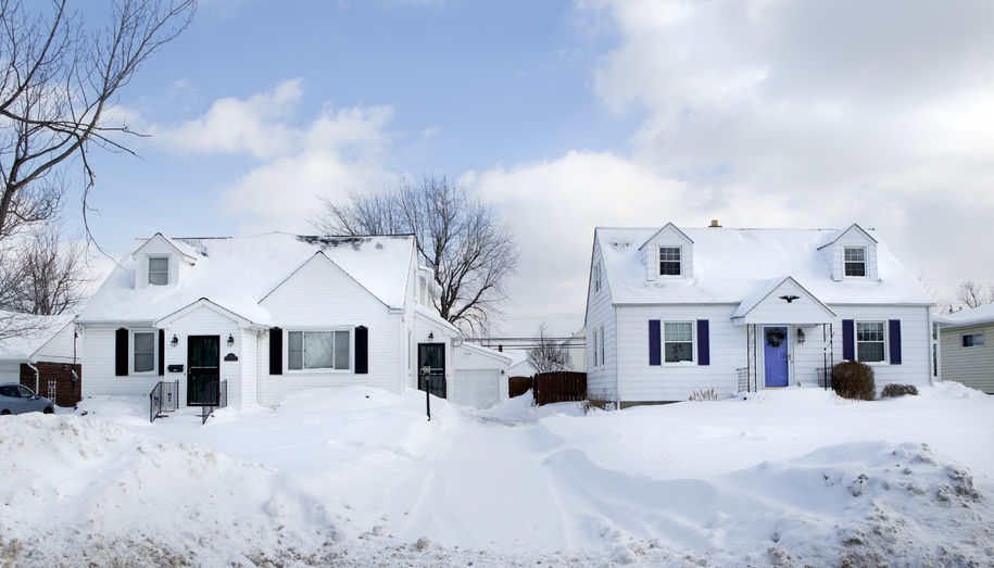 Two houses in a suburban neighborhood covered in fresh snow